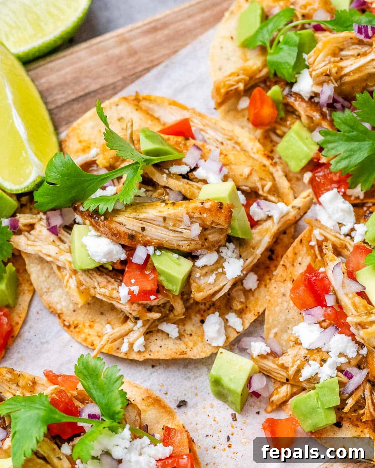 Fiesta Chicken Tostadas 8 Two generously topped chicken tostadas on a wooden cutting board, adorned with fresh cilantro and creamy avocado slices, highlighting their fresh appeal.