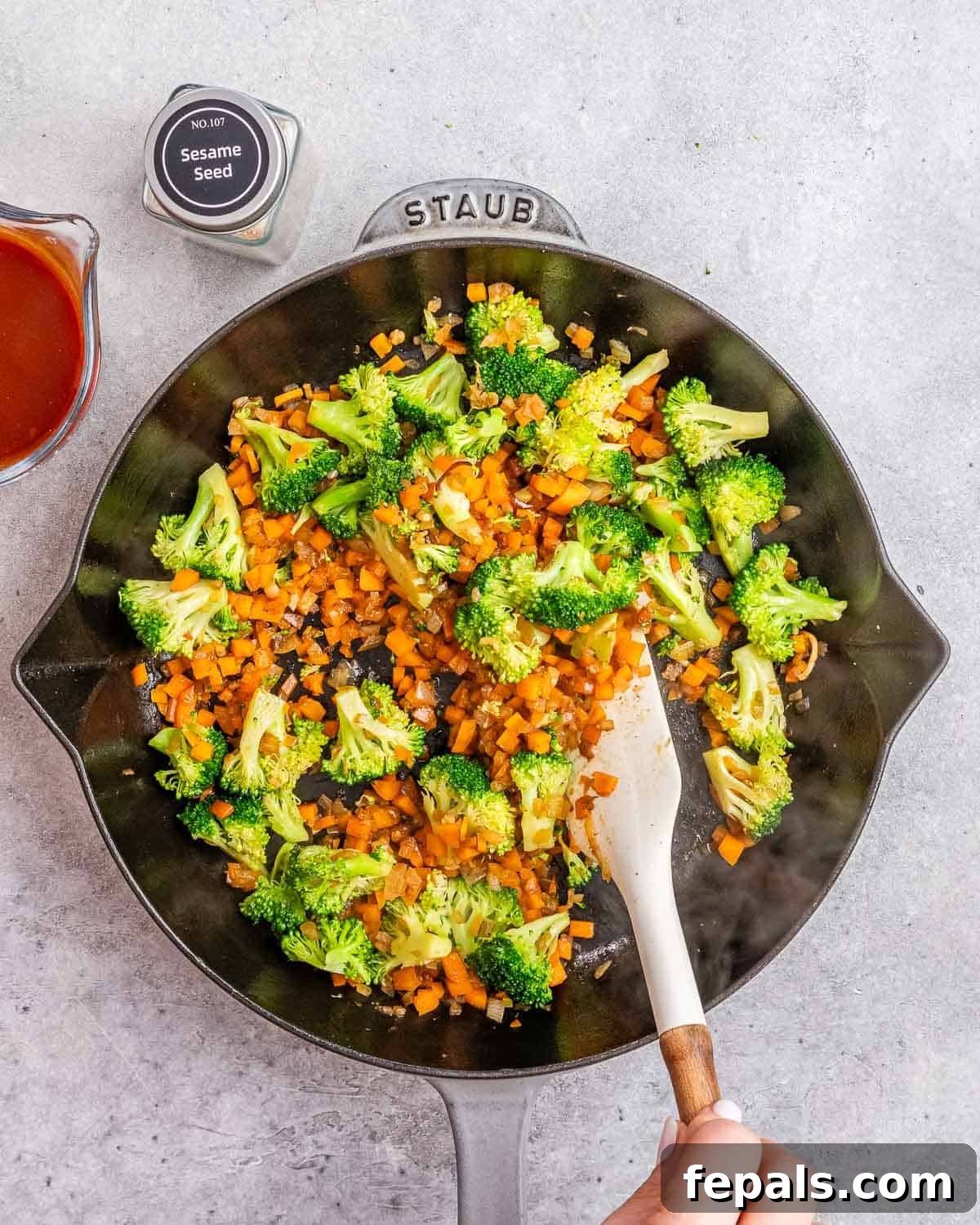 Wok-Tossed Beef Noodles 6 A mix of chopped carrots, broccoli, and onions being stir-fried in a skillet with garlic.