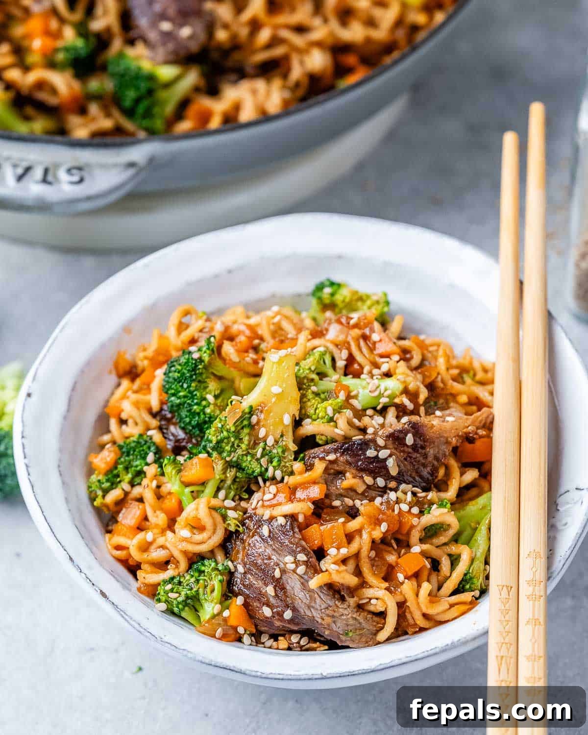 Wok-Tossed Beef Noodles 9 A serving of Beef Lo Mein in a white bowl, with wooden chopsticks resting on the side, ready to be eaten.