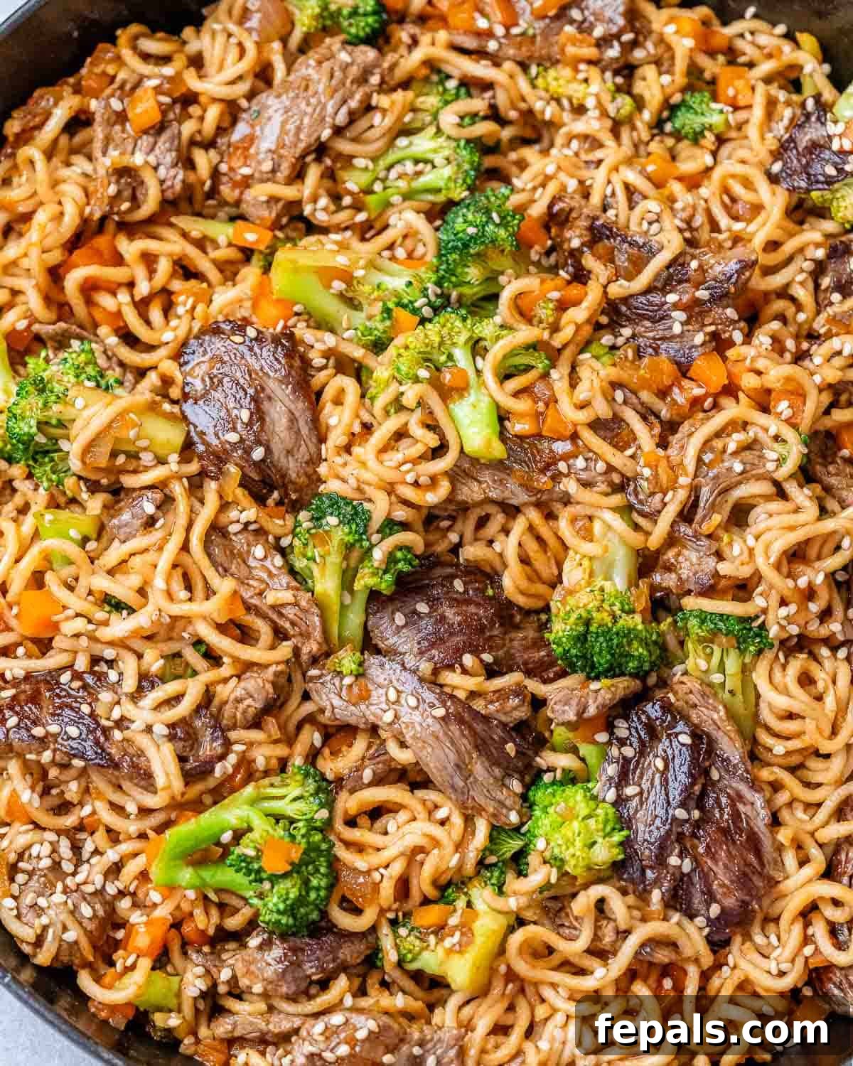 Wok-Tossed Beef Noodles 10 Close up of delicious beef lo mein in a skillet, showcasing the noodles, beef, and colorful vegetables coated in sauce.