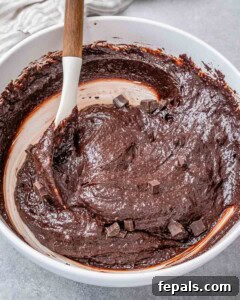 Fudgy Almond Flour Brownies 16 chocolate chunks are added to the brownie batter in a white bowl.