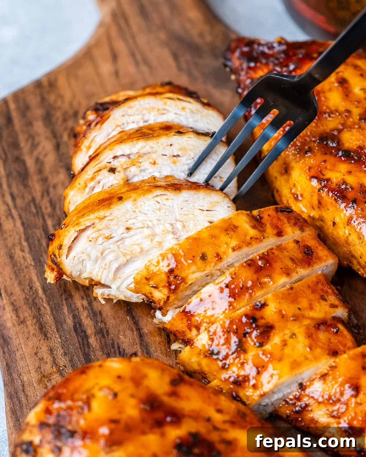 Air Fryer Frozen Chicken Breast Magic 2 A fork picking up a slice of chicken from a cutting board.