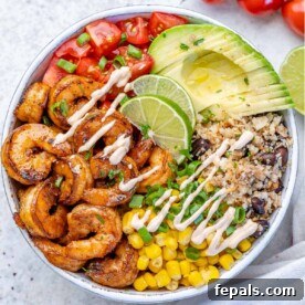 A top-down view of a vibrant shrimp burrito bowl, generously filled with creamy avocado, fluffy cauliflower rice, ripe tomatoes, and sweet corn, offering a low-carb and flavorful option.