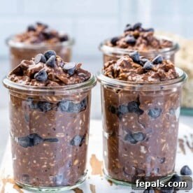 Four jars of decadent chocolate overnight oats, generously topped with chocolate chips, a perfect healthy indulgence.