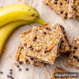 A top-down view of wholesome oatmeal bar squares, gracefully stacked upon each other, with a ripe banana artfully placed in the top left corner for a delightful presentation.