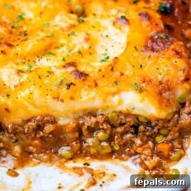 Shepherds pie in a white baking dish with meat showing at the bottom and potatoes on top.