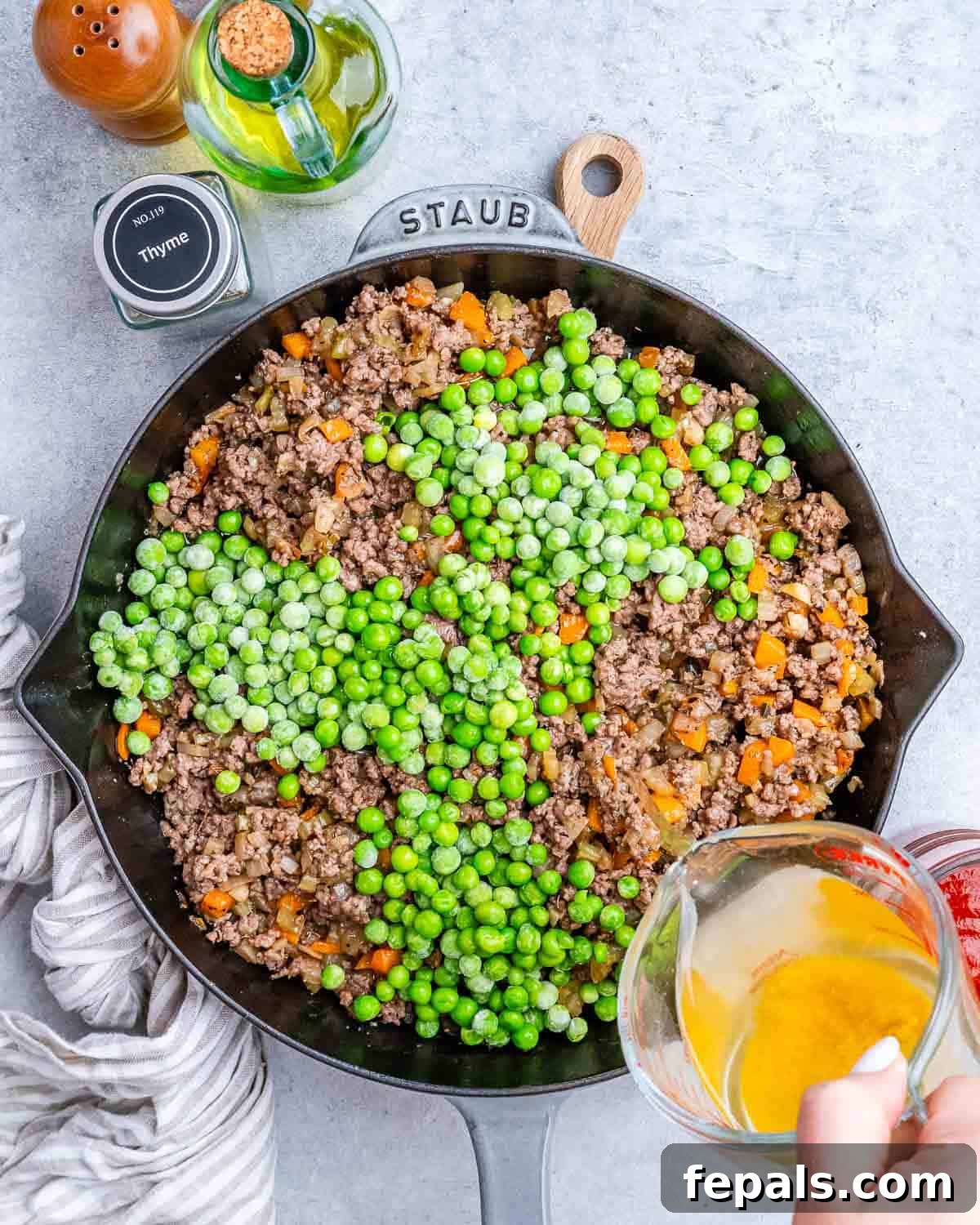 Homestyle Beef Shepherd's Delight 6 Pouring liquid from a measuring cup over beef and peas in a skillet.