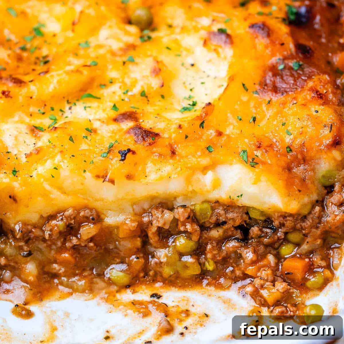 Homestyle Beef Shepherd's Delight 10 Shepherds pie in a white baking dish with meat showing at the bottom and potatoes on top.