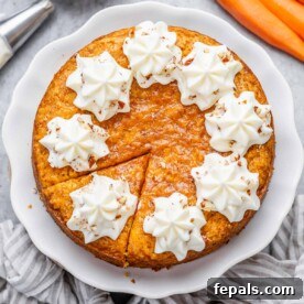 Effortless Carrot Cake 12 round carrot cake with slice cut off topped with creamy cheese frosting.
