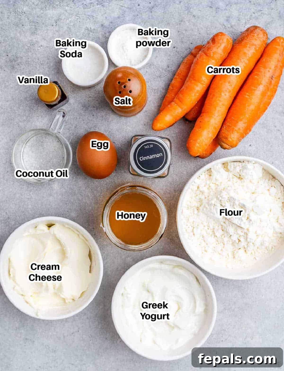 Effortless Carrot Cake 4 A flat lay of fresh ingredients for carrot cake, including grated carrots, flour, eggs, and cream cheese.