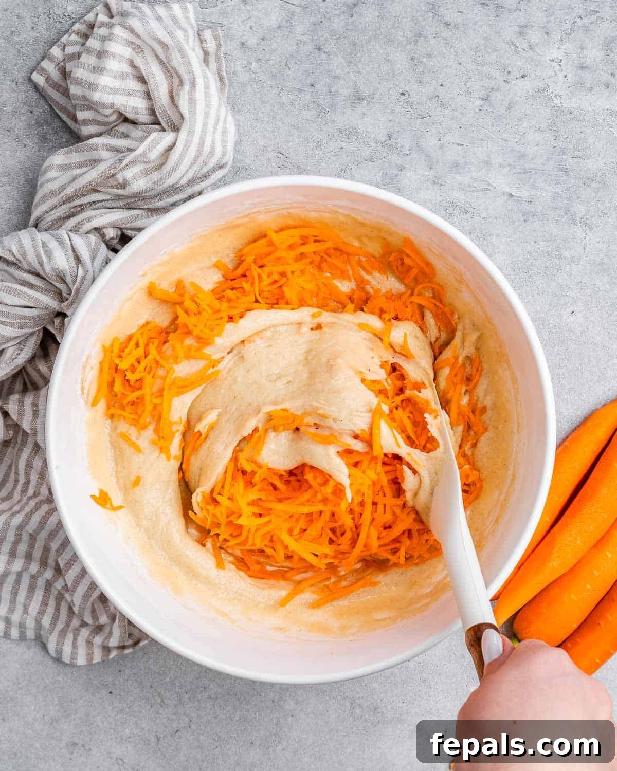 Effortless Carrot Cake 6 A spatula stirring in carrots to cake batter.