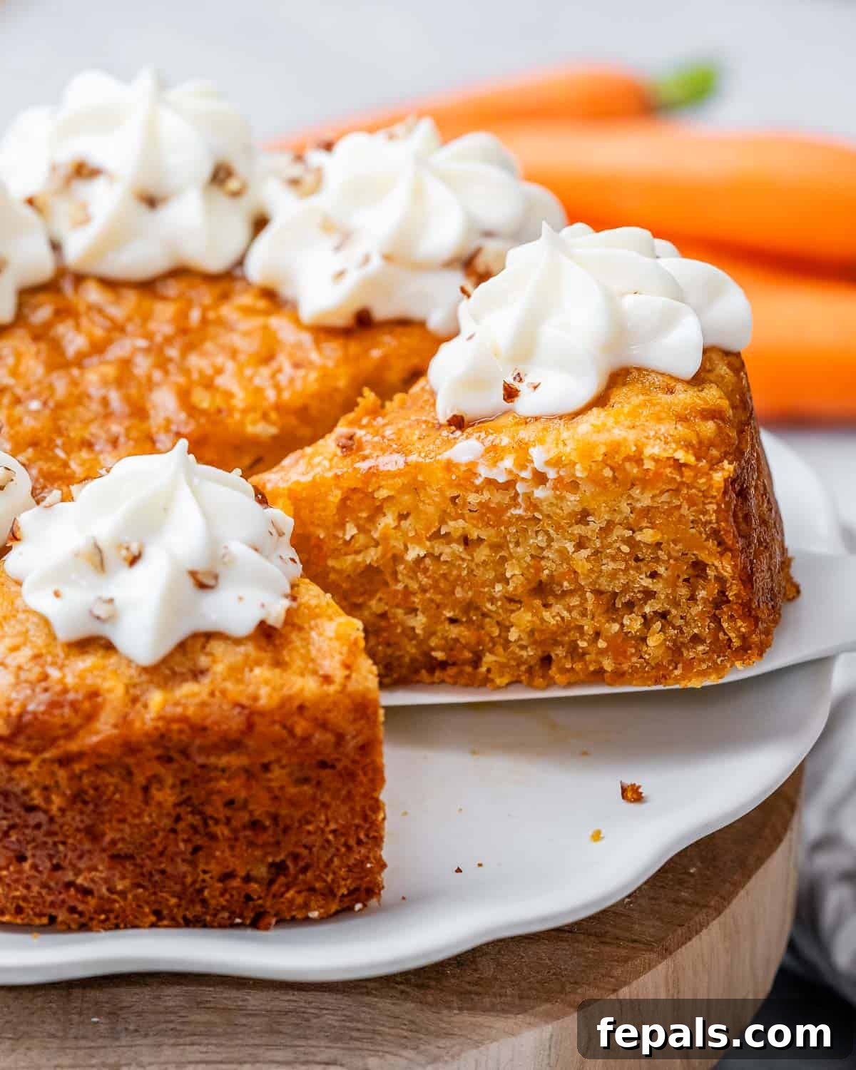 Effortless Carrot Cake 9 A spatula lifting a slice of frosted carrot cake away from the rest of the cake.