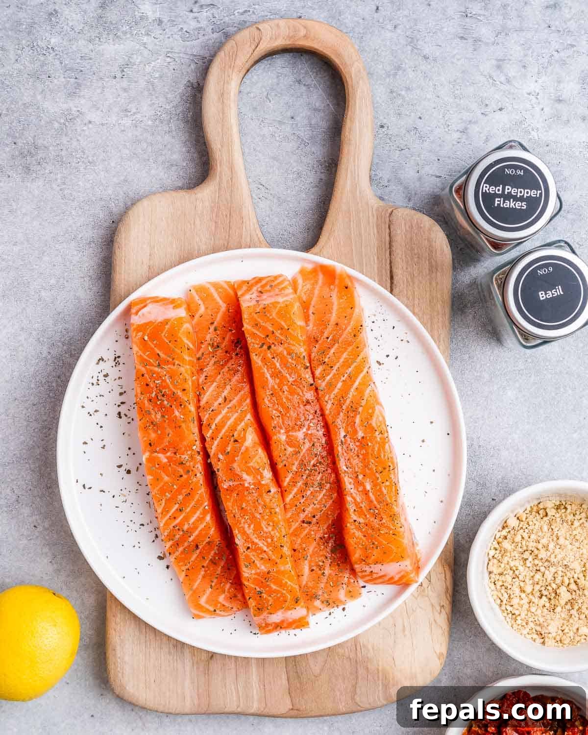 Proposal Salmon 4 Salmon fillets being seasoned on a plate with spices.