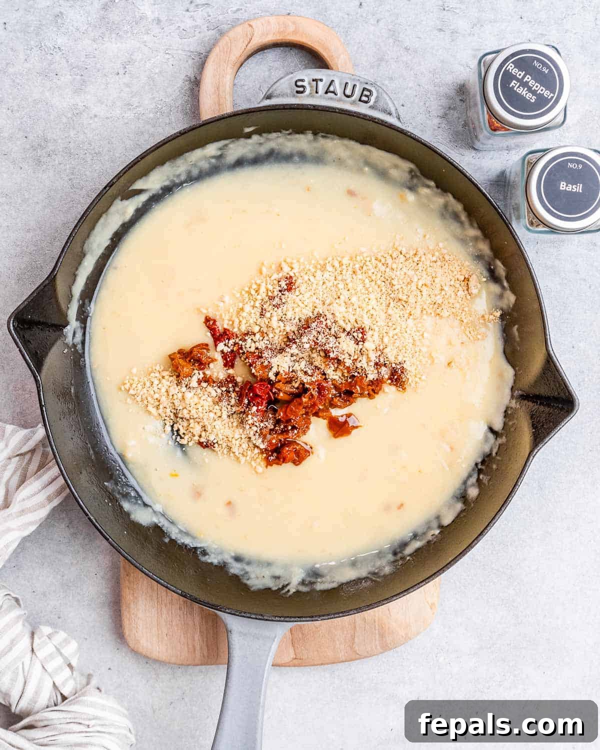 Proposal Salmon 6 A creamy sauce simmering in a black skillet with vibrant sun-dried tomatoes.