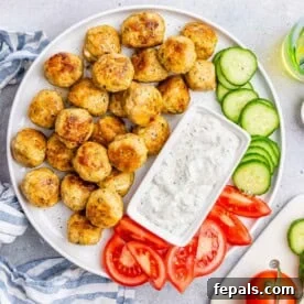 Close-up of Greek Turkey Meatballs on a plate with fresh vegetables and tzatziki sauce.