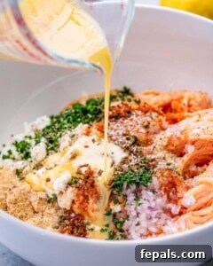 A measuring cup pouring sauce over a white bowl of ingredients.