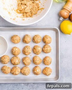 Meatballs lined up on a baking sheet.