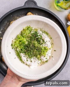 A hand holding a bowl with green herbs.