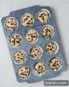 muffin batter is added to a pan and topped with chocolate chips.