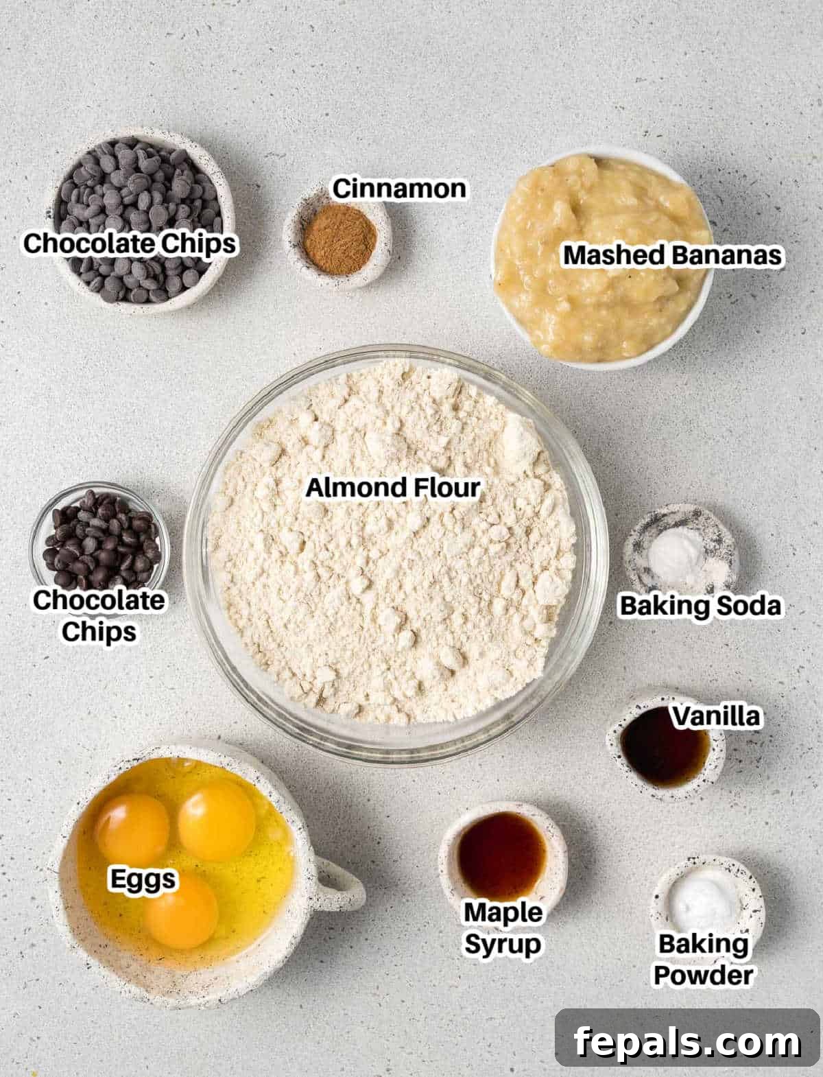 A selection of fresh ingredients including ripe bananas, eggs, almond flour, maple syrup, and chocolate chips, ready for making banana muffins.