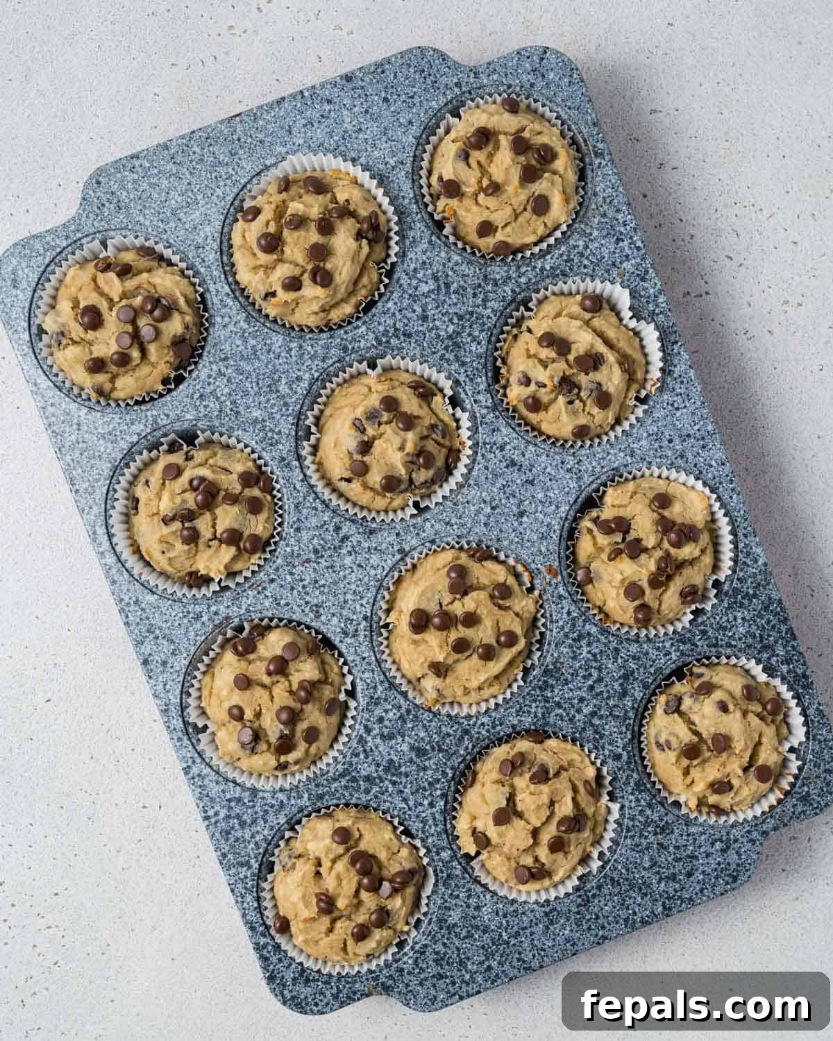 A tray of freshly baked, golden-brown almond flour banana muffins cooling in the muffin pan.