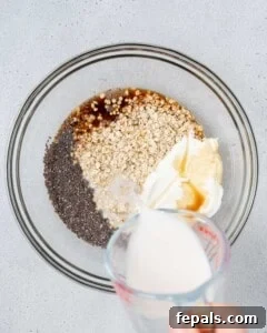 Milk being poured into a bowl with oats, chia, and yogurt.
