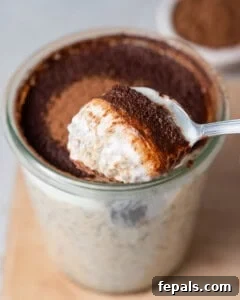 A jar with overnight oats topped with cocoa powder and a spoonful of the oats.