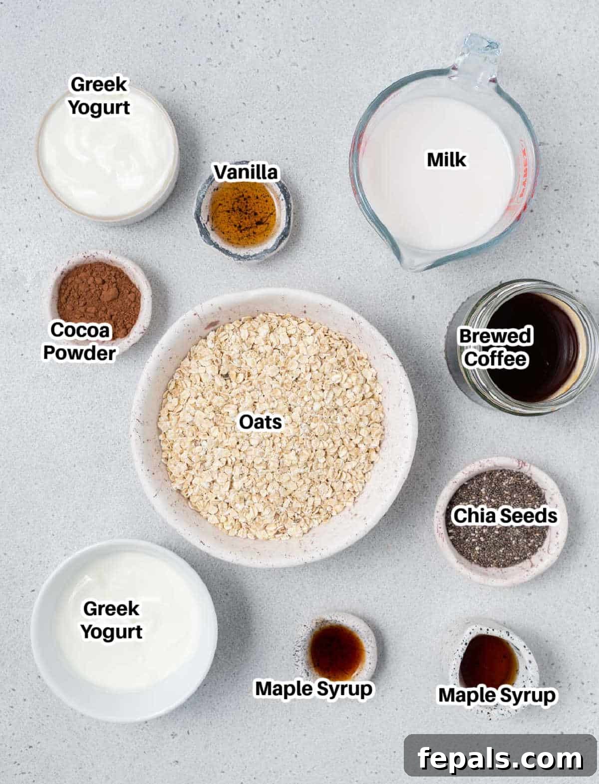 Creamy Tiramisu Overnight Oats 3 A selection of ingredients laid out on a wooden board, including oats, chia seeds, coffee, milk, Greek yogurt, vanilla extract, and maple syrup, ready to make tiramisu overnight oats.