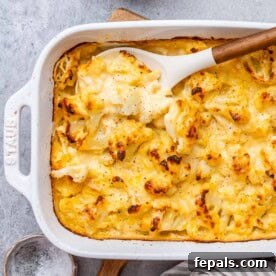 Mac and cheese with cauliflower in a white dish with spoon in the dish.