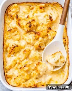 Mac and cheese with cauliflower in a white dish with spoon in the dish.