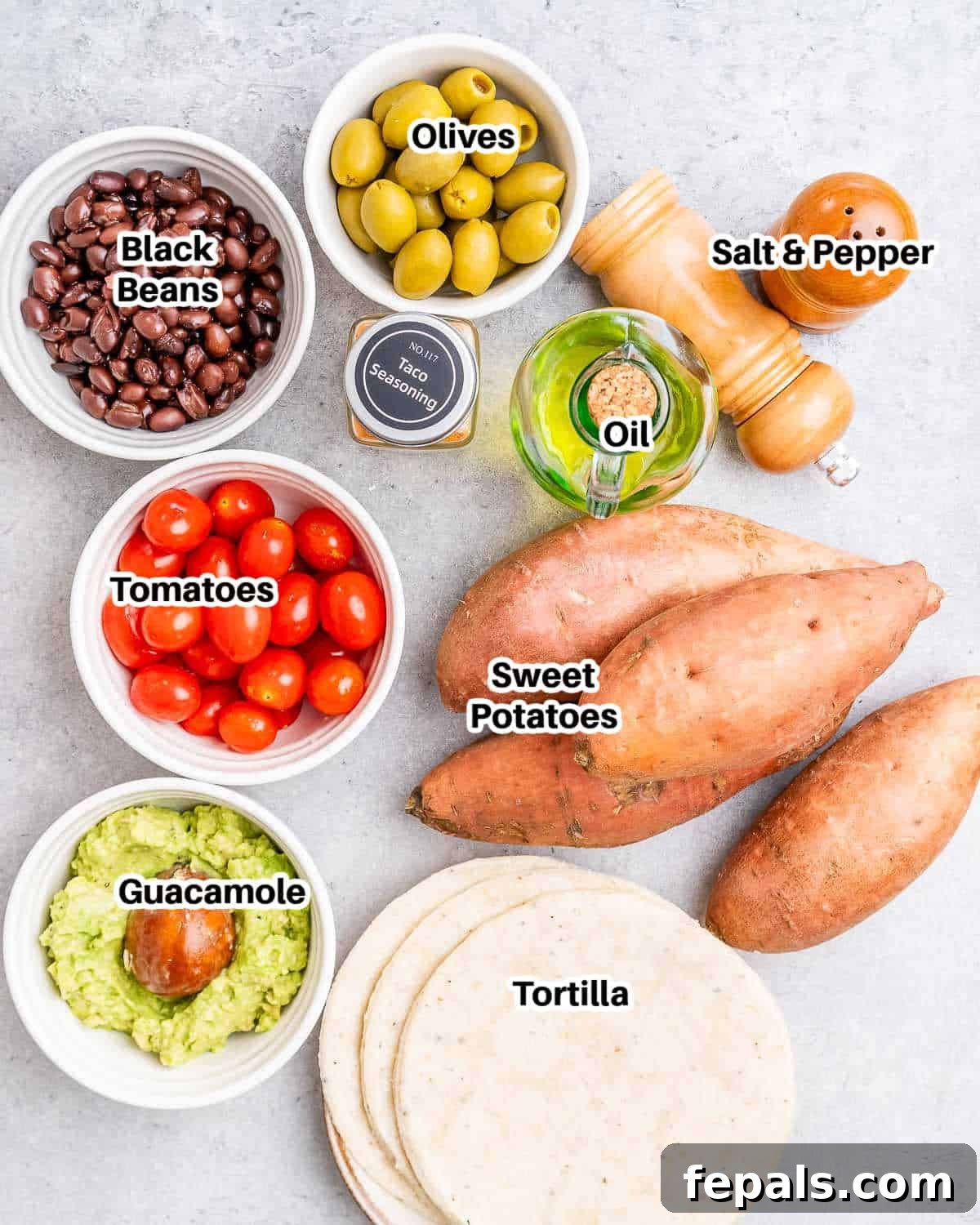 A flat lay of fresh ingredients for black bean sweet potato tacos, including diced sweet potatoes, canned black beans, ripe avocados for guacamole, fresh cilantro, cherry tomatoes, and lime wedges.