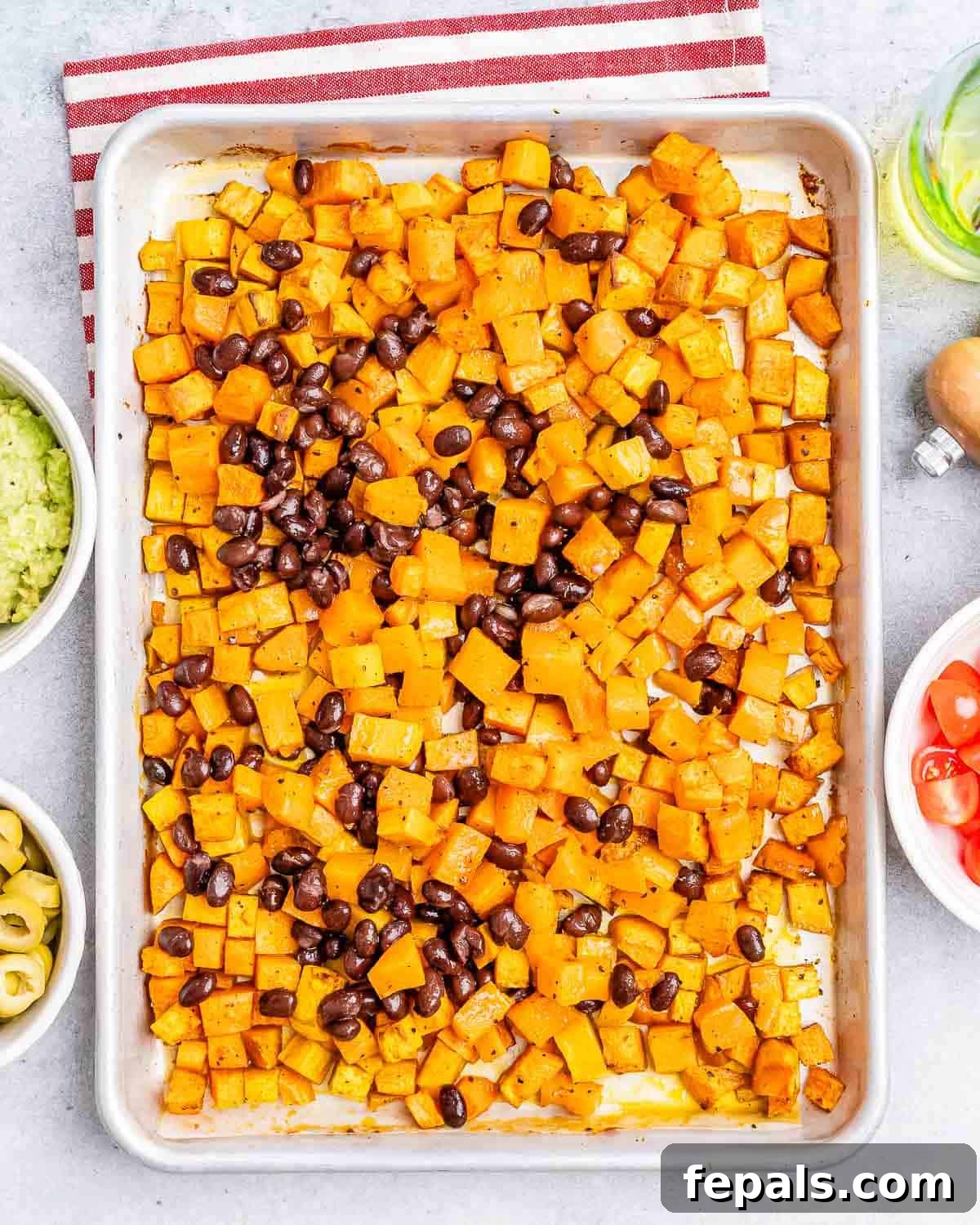 Roasted diced sweet potatoes mixed with black beans on a baking sheet, fresh out of the oven.