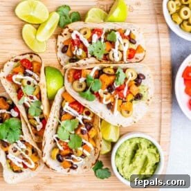 4 tacos filled with black beans and sweet potatoes on a cutting board.