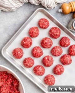 Uncooked meatballs on a baking sheet.
