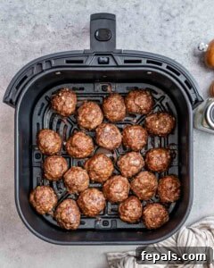An air fryer basket filled with cooked meatballs.