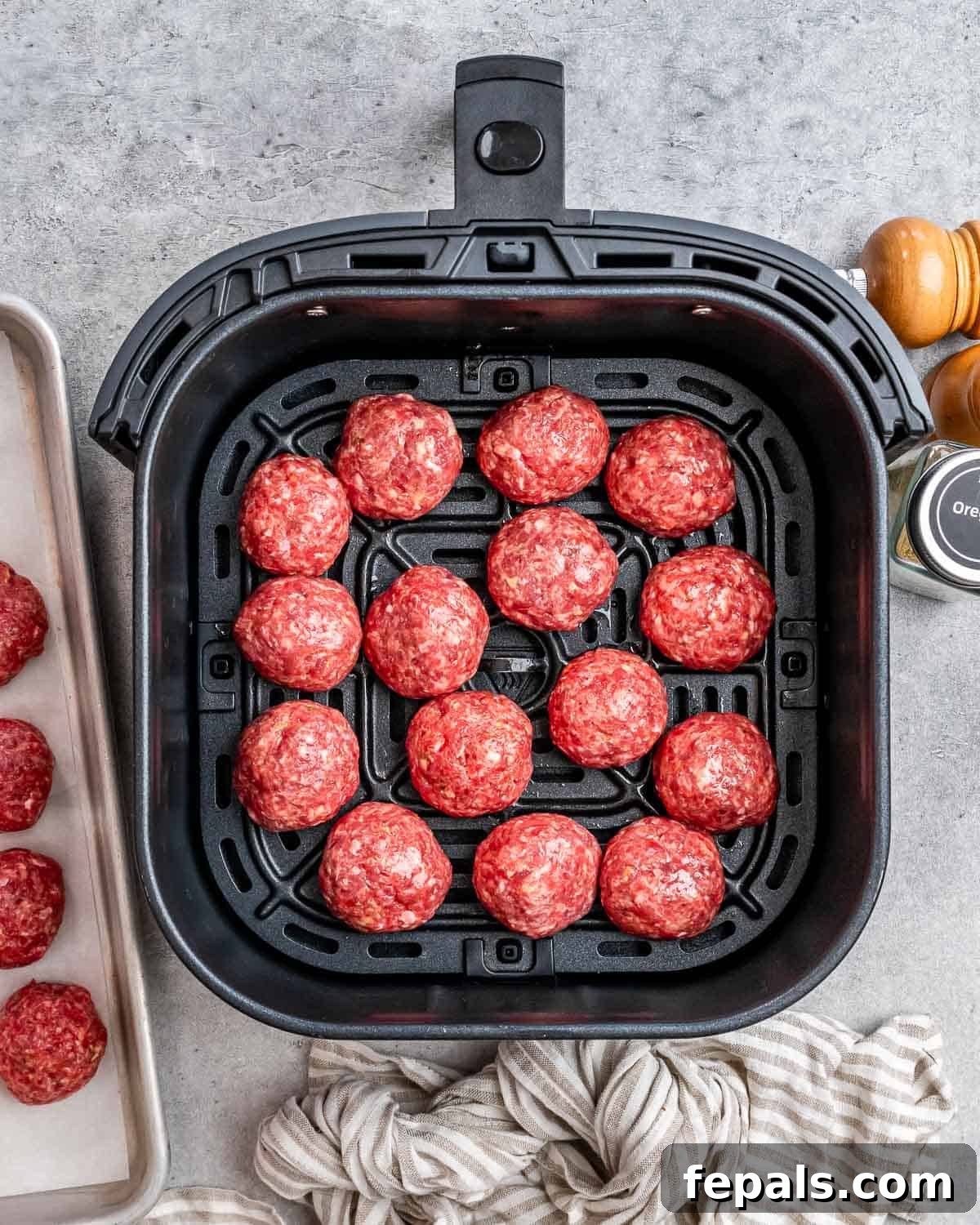 Golden Air Fryer Meatballs 6 An air fryer basket filled with a single layer of uncooked meatballs, ensuring ample space between each for optimal air circulation.