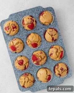 Unbaked raspberry muffins batter scooped into a muffin pan, ready for the oven.