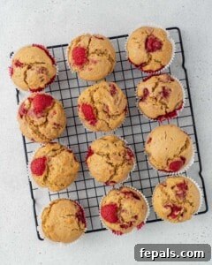Baked raspberry muffins are placed on a wire rack to cool.