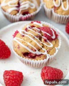 A finished raspberry muffin on a plate, beautifully topped with a sweet sugar glaze.