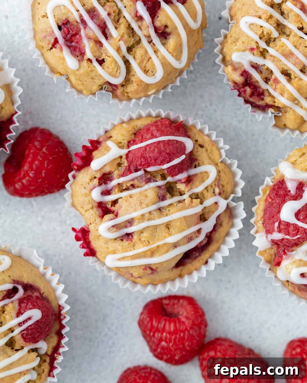 A single beautifully glazed raspberry muffin placed on a rustic flat surface, ready to be enjoyed.