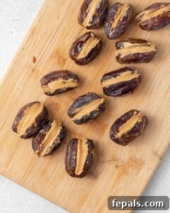 A cutting board with halved, pitted dates with peanut butter in them.