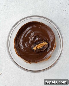 A single date being dipped in the bowl of melted chocolate