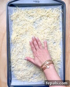 Golden Crunch Onion Rings 13 hand spreading shredded parmesan on a sheet pan.