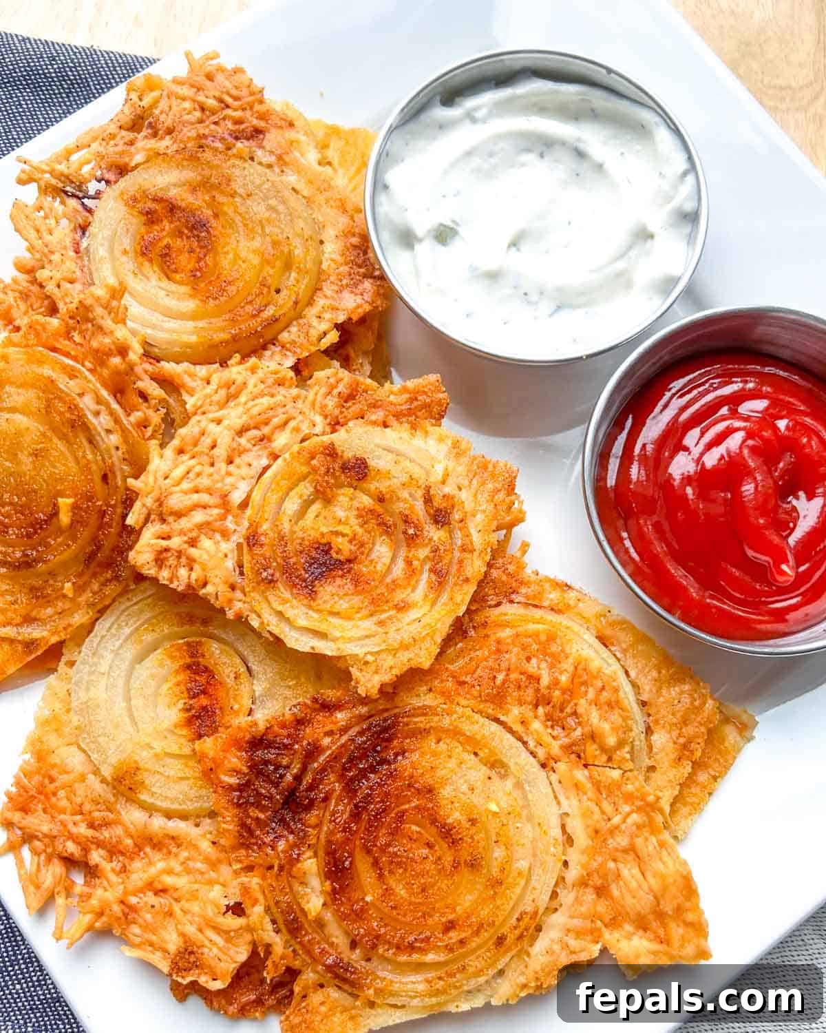 Golden Crunch Onion Rings 8 A platter of crispy onion ring chips served with two distinct dipping sauces: a creamy white sauce and vibrant red ketchup.