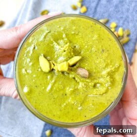 Decadent Pistachio Cream 15 Hand holding a jar of vibrant homemade pistachio cream.