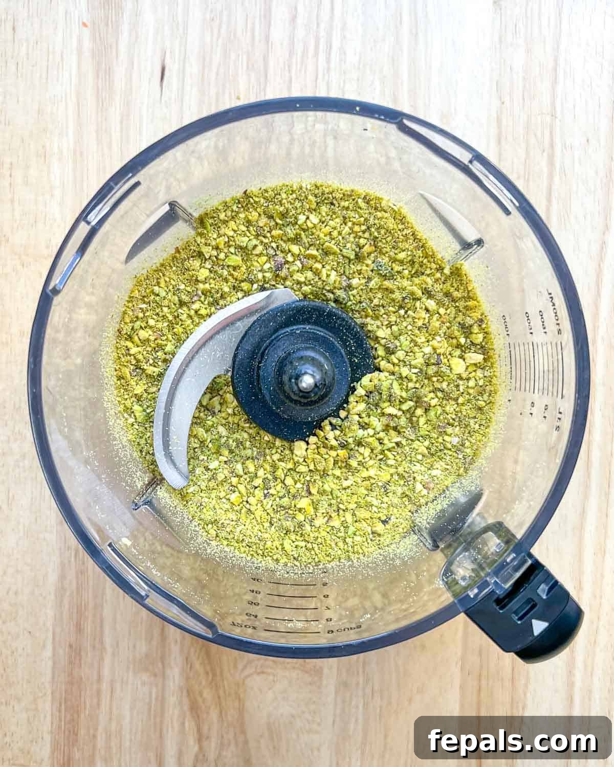 Decadent Pistachio Cream 5 Pistachios halfway processed in a blender, showing a coarse, crumbly texture.