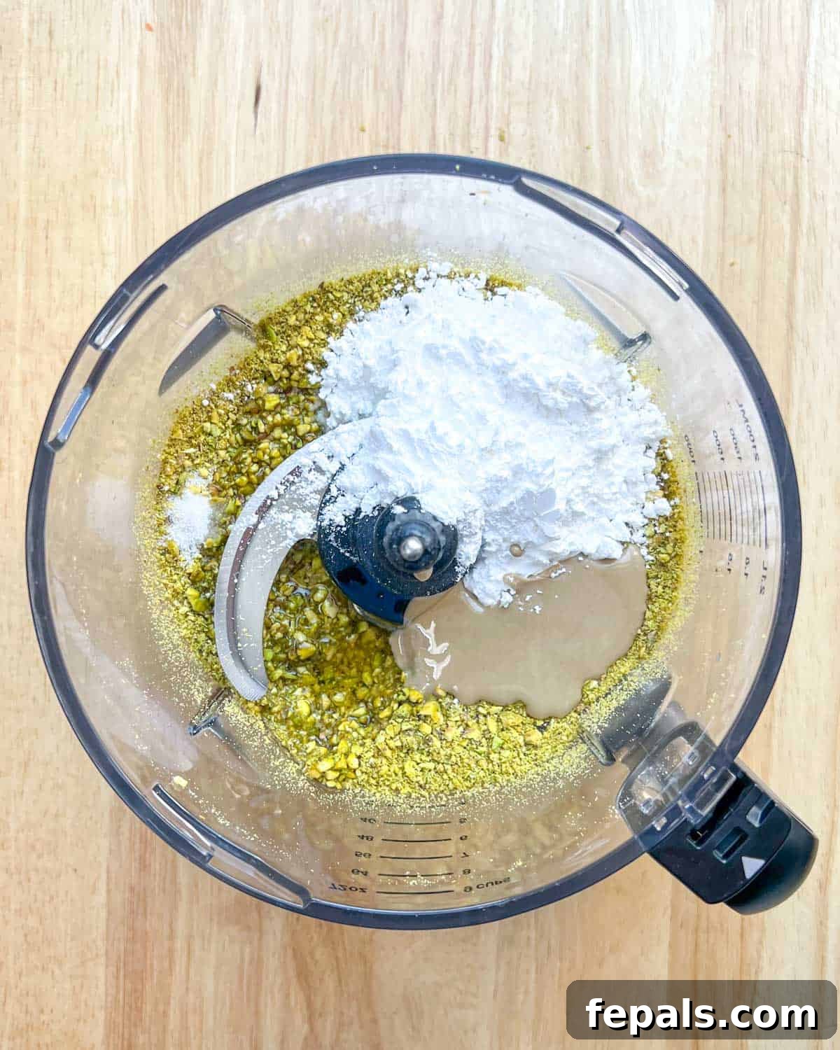 Decadent Pistachio Cream 6 Powdered sugar, tahini, salt, and oil being added to the partially blended pistachios in the blender.