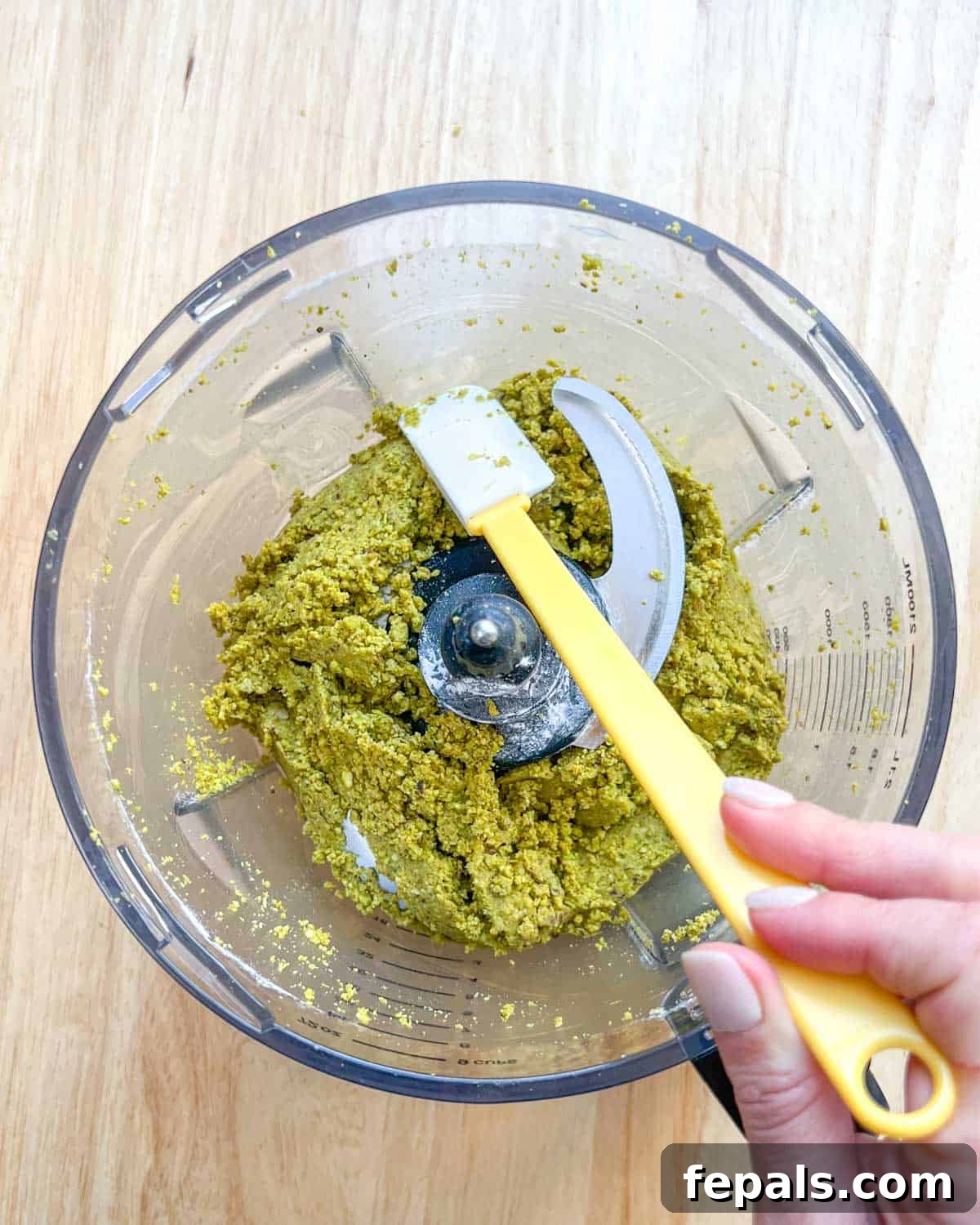 Decadent Pistachio Cream 7 A spatula scraping down the sides of the blender to ensure all pistachio mixture is incorporated for even blending.