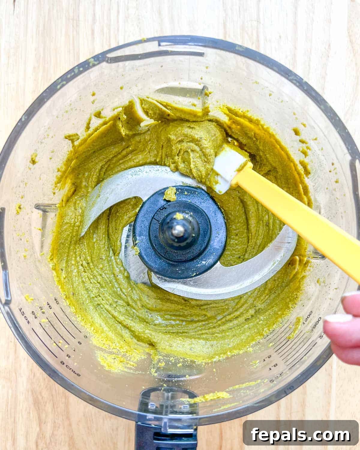 Decadent Pistachio Cream 9 A spatula carefully removing creamy homemade pistachio cream from the blender.