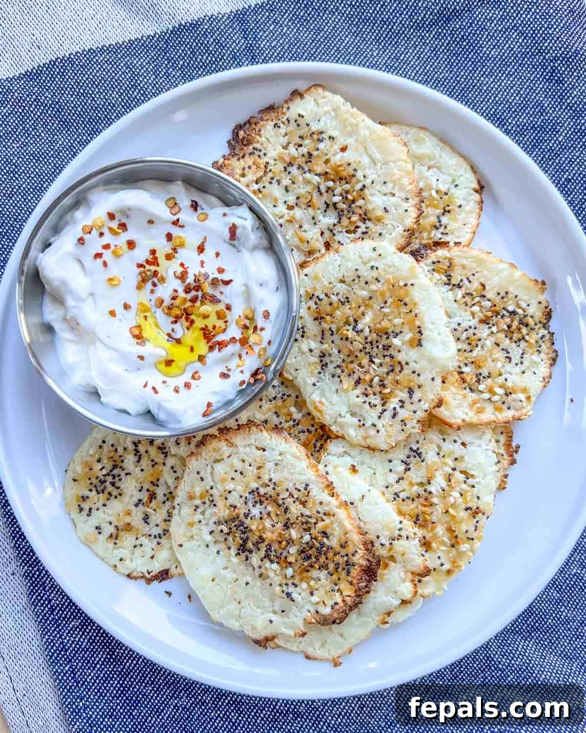 Crispy Cottage Cheese Bites 2 Crispy cottage cheese chips on a plate with a side of white dipping sauce, showcasing their golden-brown texture.